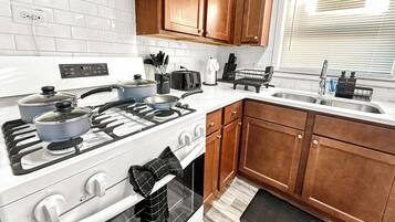 A kitchen with white appliances, wooden cabinets, a stove, oven, and a sink.