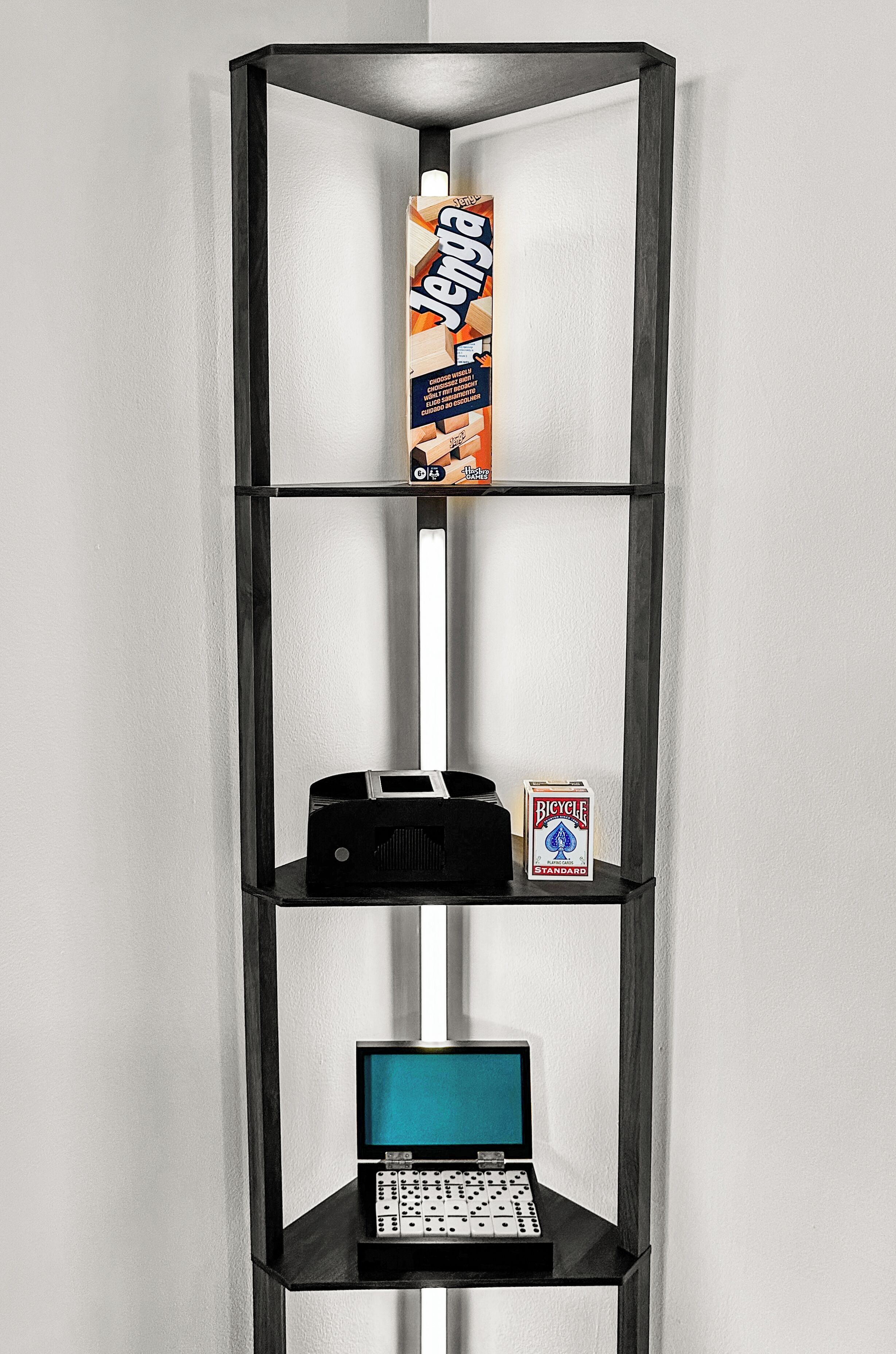 A corner shelf unit with a carton of juice, a dice set, and a laptop.