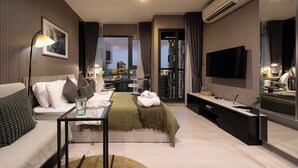 Une chambre d’hôtel moderne équipée d’un lit, d’un canapé, d’une télévision et d’un bureau avec une lampe.