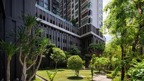 Un bâtiment moderne doté d’une cour intérieure agrémentée d’une pelouse bien entretenue, de divers arbres et d’un sentier.
