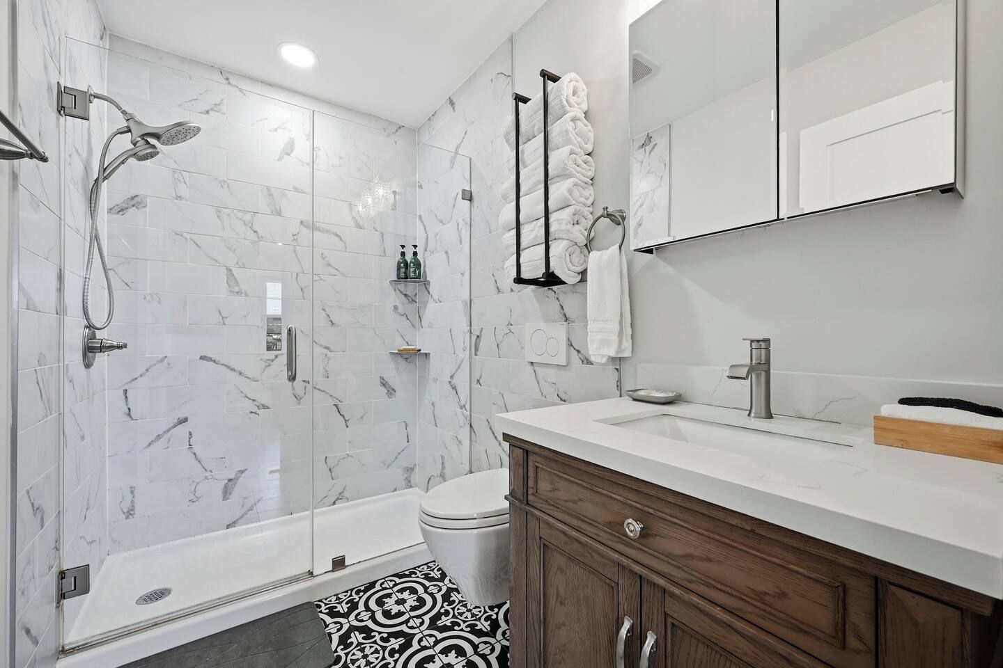 A modern bathroom with a shower, toilet, vanity, and a large mirror.