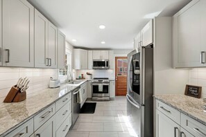 A modern kitchen with white cabinetry, stainless steel appliances, and a granite countertop.