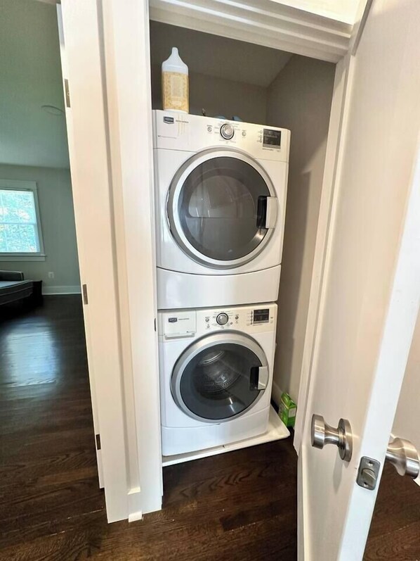 A laundry room with two stacked front-loading washing machines and a bottle of detergent on top. - Downtown Retreat with 2 Primary Suites (Leesburg)