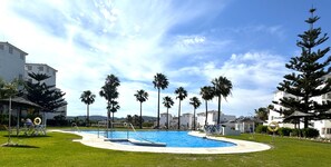 Une piscine entourée de palmiers et de bâtiments blancs.
