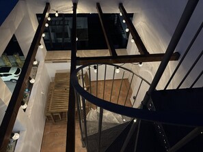 Un escalier en colimaçon avec une rampe en bois et une vue sur une voiture garée à l’extérieur.