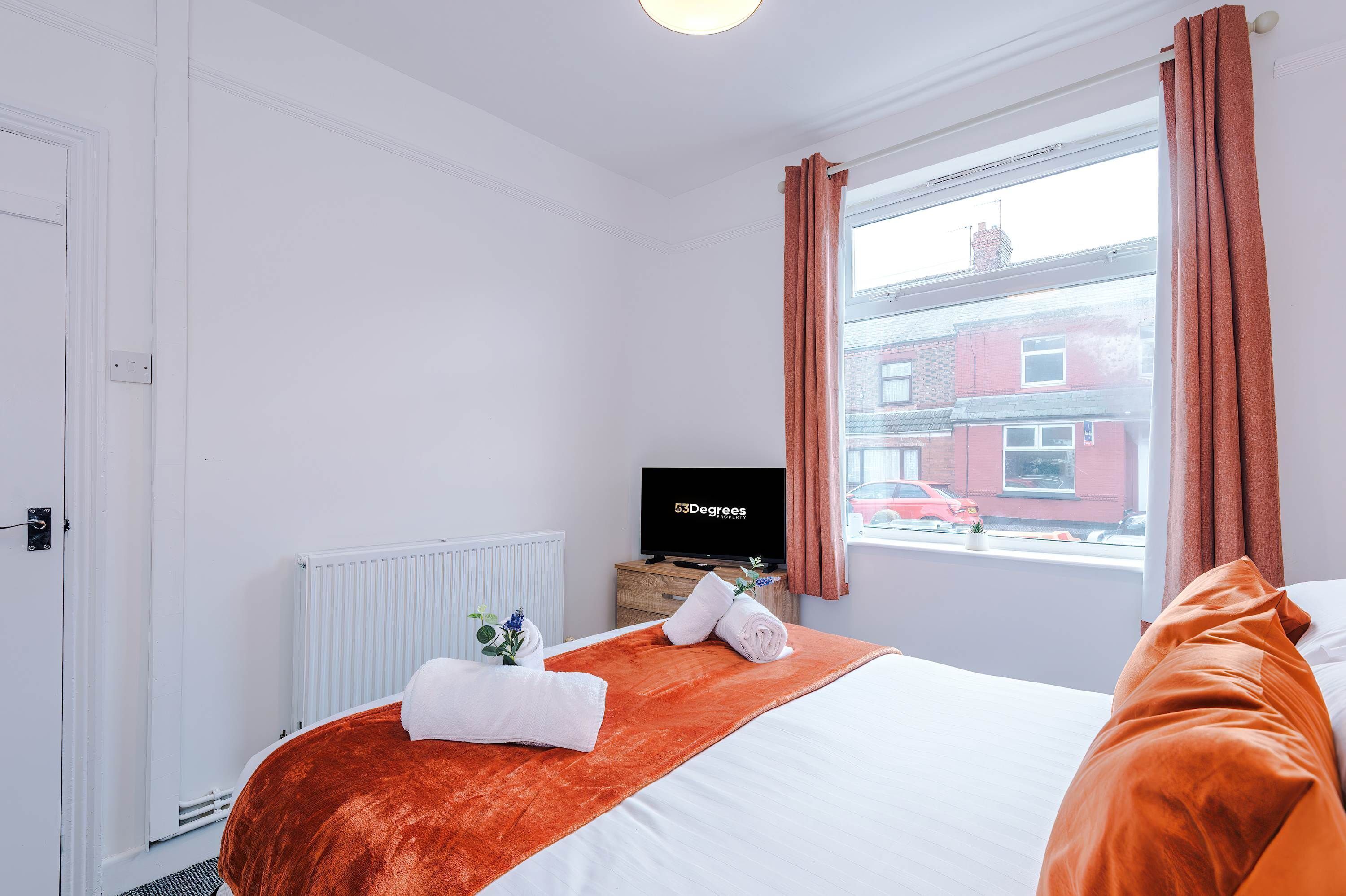 Une chambre d’hôtel avec un lit, une télévision, une fenêtre avec des rideaux et un radiateur.