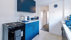 A modern kitchen with blue cabinets, a stove, and a microwave. - Great 3-bed Home Perfect for Work Contractors (Ellesmere Port)