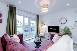 A modern living room with a sofa set, a flat-screen TV, a dining table, and a view of the outside. - Centrally Located Flat off Formby High Street (Liverpool)