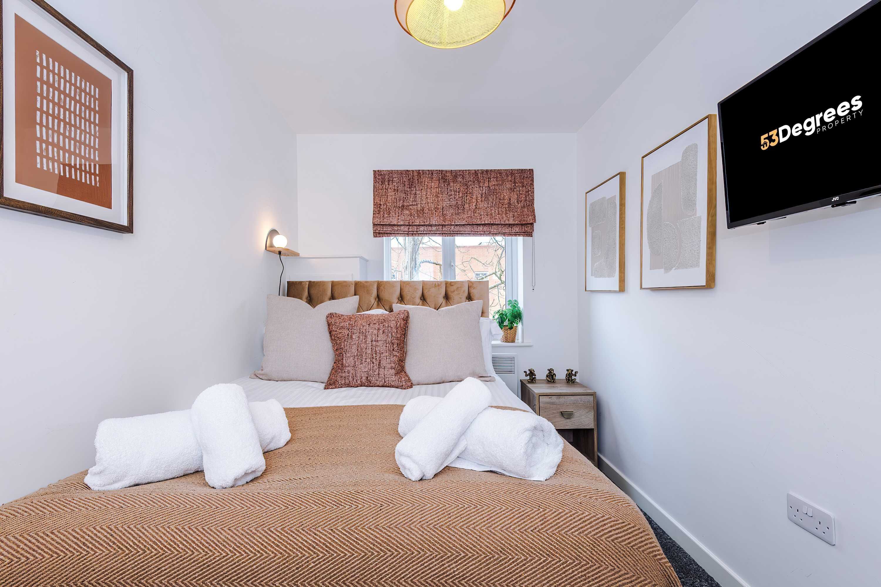 Une chambre d’hôtel équipée d’un lit, d’une télévision, d’une fenêtre avec vue et d’un téléviseur fixé au mur qui diffuse des images de « 53 Degrees Property ».