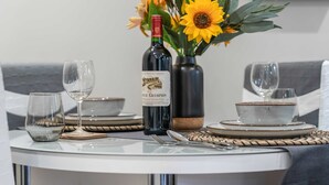 A dining table set with wine glasses, plates, and a bottle of wine, accompanied by a vase of sunflowers. - Stylish 1 Bed Flat in Birmingham City Centre (Birmingham)