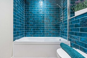 Ein Badezimmer mit einer Badewanne, weißen Wänden und blauen Fliesen.