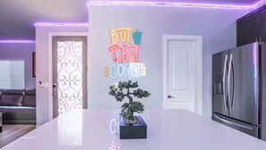 Una cucina moderna con un neon, un frigorifero e un bonsai sull'isola.