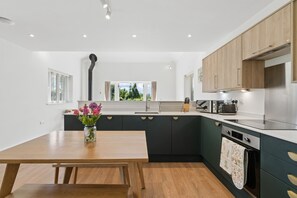 Eine moderne Küche mit einem Holztisch, einer Blumenvase und Blick auf Grün.