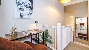 A staircase with a white railing, a wooden table with a lamp, a framed picture on the wall, and a brown sofa. - Charming City Centre 3 Bed Flat High St Location (Chester)