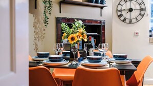 A dining area with a table set for four, a large wall clock, and a fireplace. - Charming City Centre 3 Bed Flat High St Location (Chester)