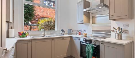 A modern kitchen with a built-in oven, a window with a view of a brick building, and a sink.