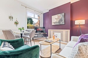 A modern living room with a fireplace, a television, and a dining area. - Beautiful Large Home in Cradley Heath Sleeps 8 (Cradley Heath)
