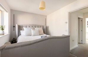 A bedroom with a bed, bedside tables, a lamp, and a window. - Modern 2 Bedroom Home in Swansea Near Stadium (Swansea)