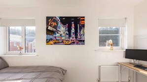 A bedroom with a bed, a desk with a computer, two windows, and a cityscape painting. - Modern 2 Bedroom Home in Swansea Near Stadium (Swansea)