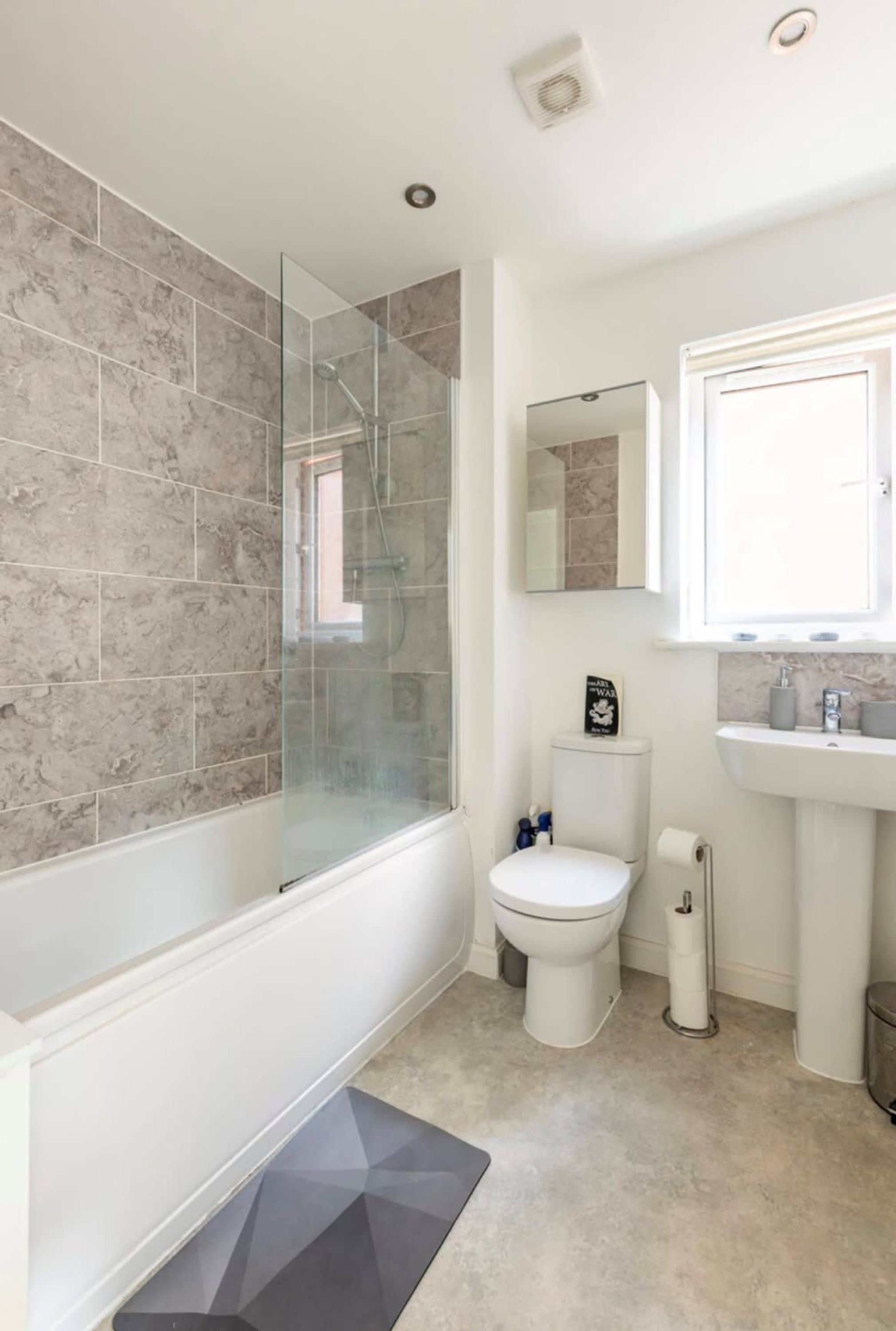 A bathroom with a glass-enclosed shower, a toilet, a sink, and a mirror.