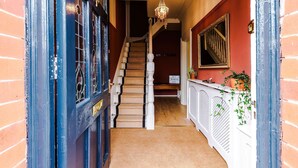 Una escalera con barandilla blanca, un candelabro y un cartel en la pared.