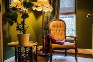 A room with a chair, a lamp, and a potted plant. - Stylish Retro Retreat in Manchester 4 Bed Home (Manchester)
