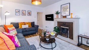 A living room with a sofa, a coffee table, a fireplace, and a television. - Spacious 3 Bed Perfect for Families and Groups (Nantwich)