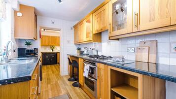Una cocina moderna con armarios de madera, encimera negra y electrodomésticos de acero inoxidable.