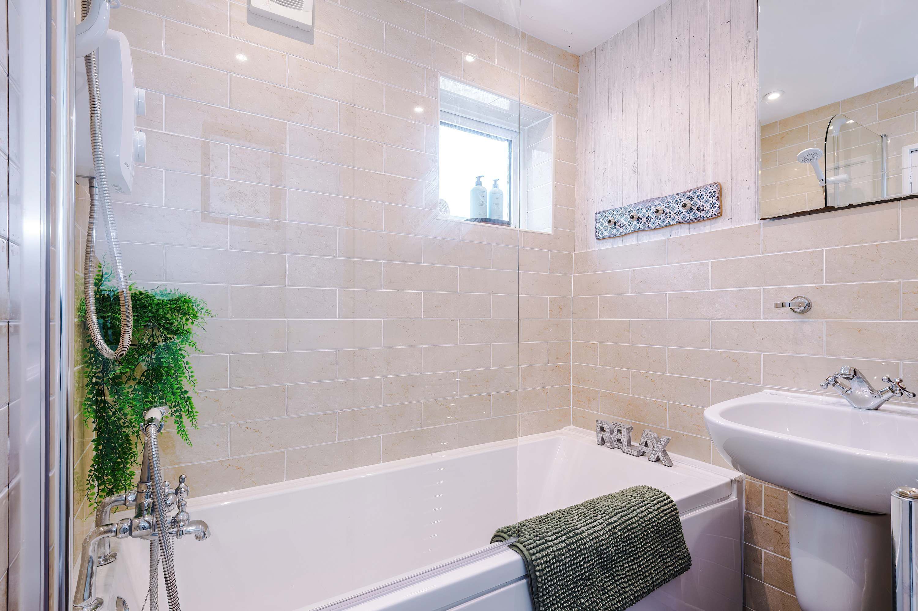 A bathroom with a bathtub, a shower, a sink, and a window.