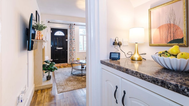 A kitchen with a granite countertop, a bowl of fruit, a lamp, and a framed picture on the wall. - Spacious 3 Bed Perfect for Families and Groups (Nantwich)