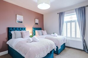 A bedroom with two beds, a large window with curtains, and artwork on the wall. - Spacious 3 Bed Perfect for Families and Groups (Nantwich)