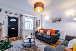 A living room with a sofa, a coffee table, a door, and a window. - Spacious 3 Bed Perfect for Families and Groups (Nantwich)