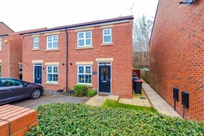 A red brick residential building with a front door, windows, and a car parked outside. - Spacious 3 Bed in Northwich Perfect for Groups (Northwich)