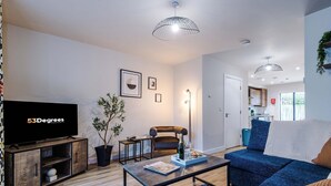 Ein modernes Wohnzimmer mit Flachbildfernseher, einer Couch, einem Couchtisch und einem Essbereich.