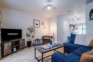 A modern living room with a flat-screen TV, a sofa, a coffee table, and a dining area. - Modern 2 Bed Manchester Stay With Parking Garden (Salford)