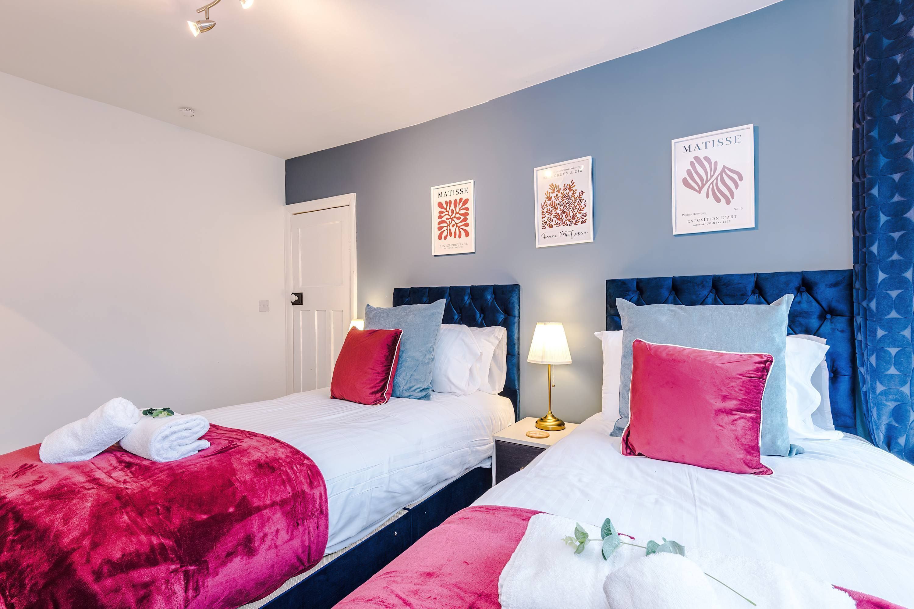 A hotel room with two beds, a red and white color scheme, and artwork on the walls.