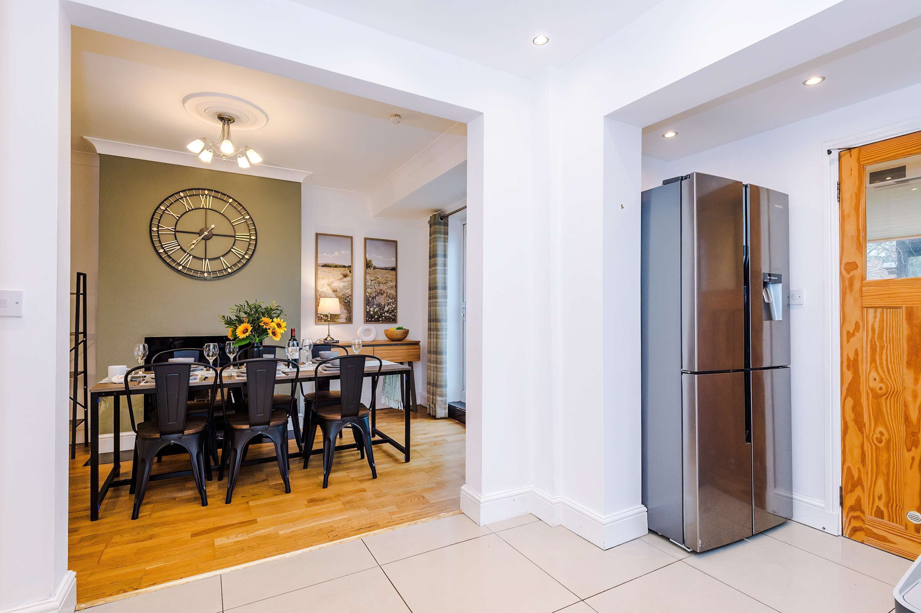 Una cocina moderna con un refrigerador de acero inoxidable, una mesa de comedor de madera y sillas.