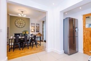 Eine moderne Küche mit einem Edelstahlkühlschrank, einem Holztisch und Stühlen.