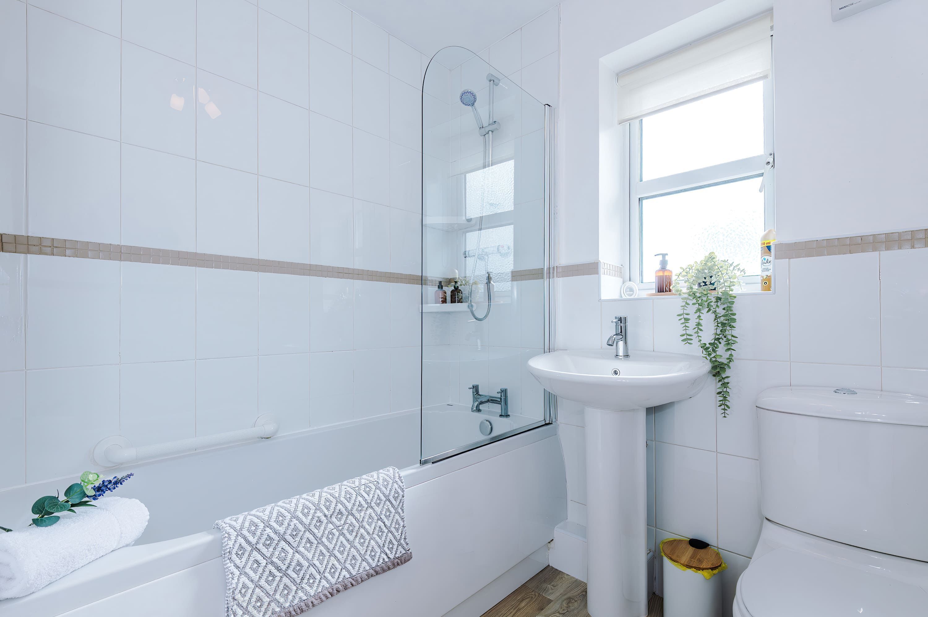 Un baño moderno con cabina de ducha de vidrio, un lavabo blanco y un inodoro.