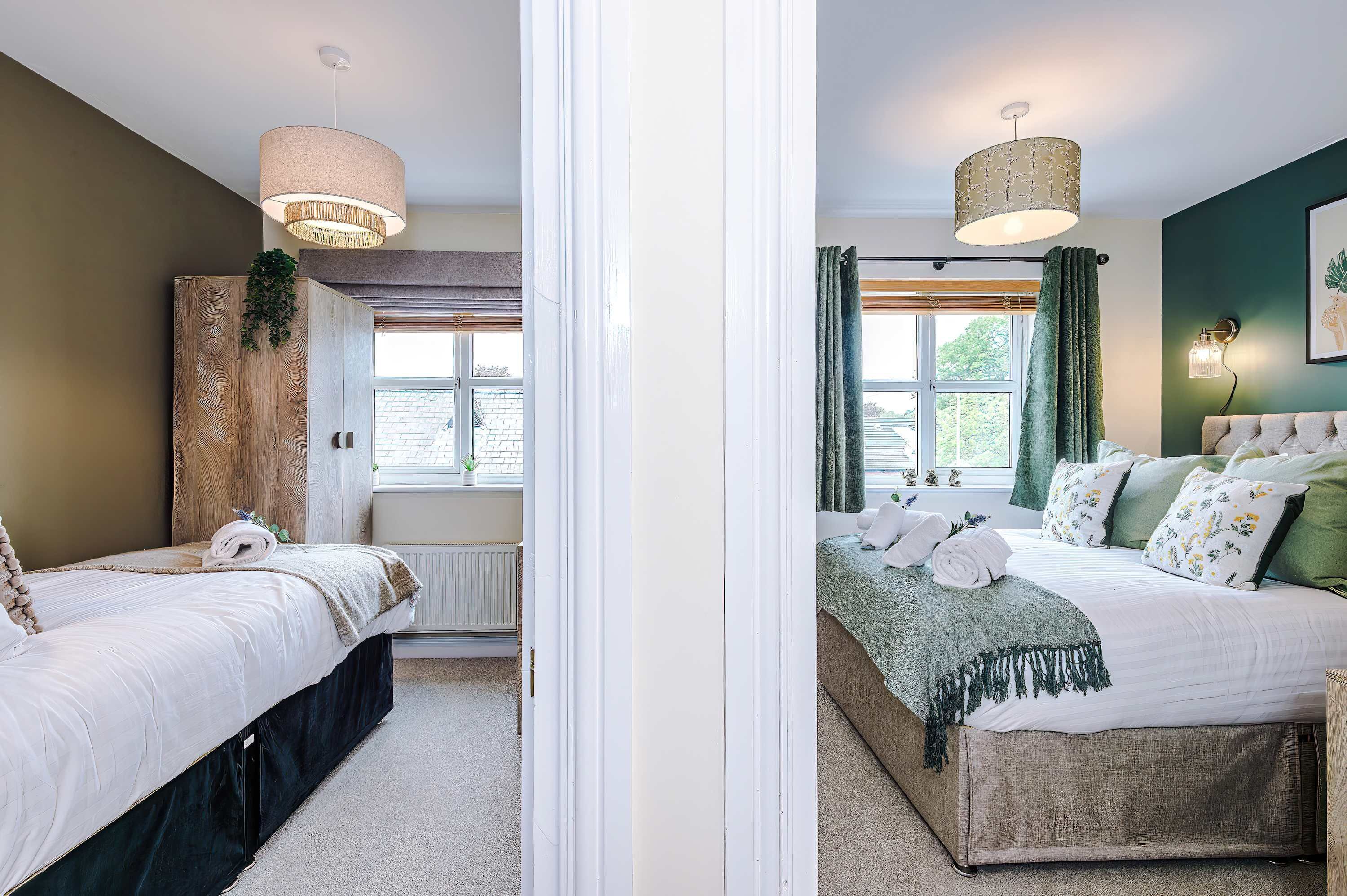 A bedroom with two beds, a window, a radiator, and a hanging light fixture.