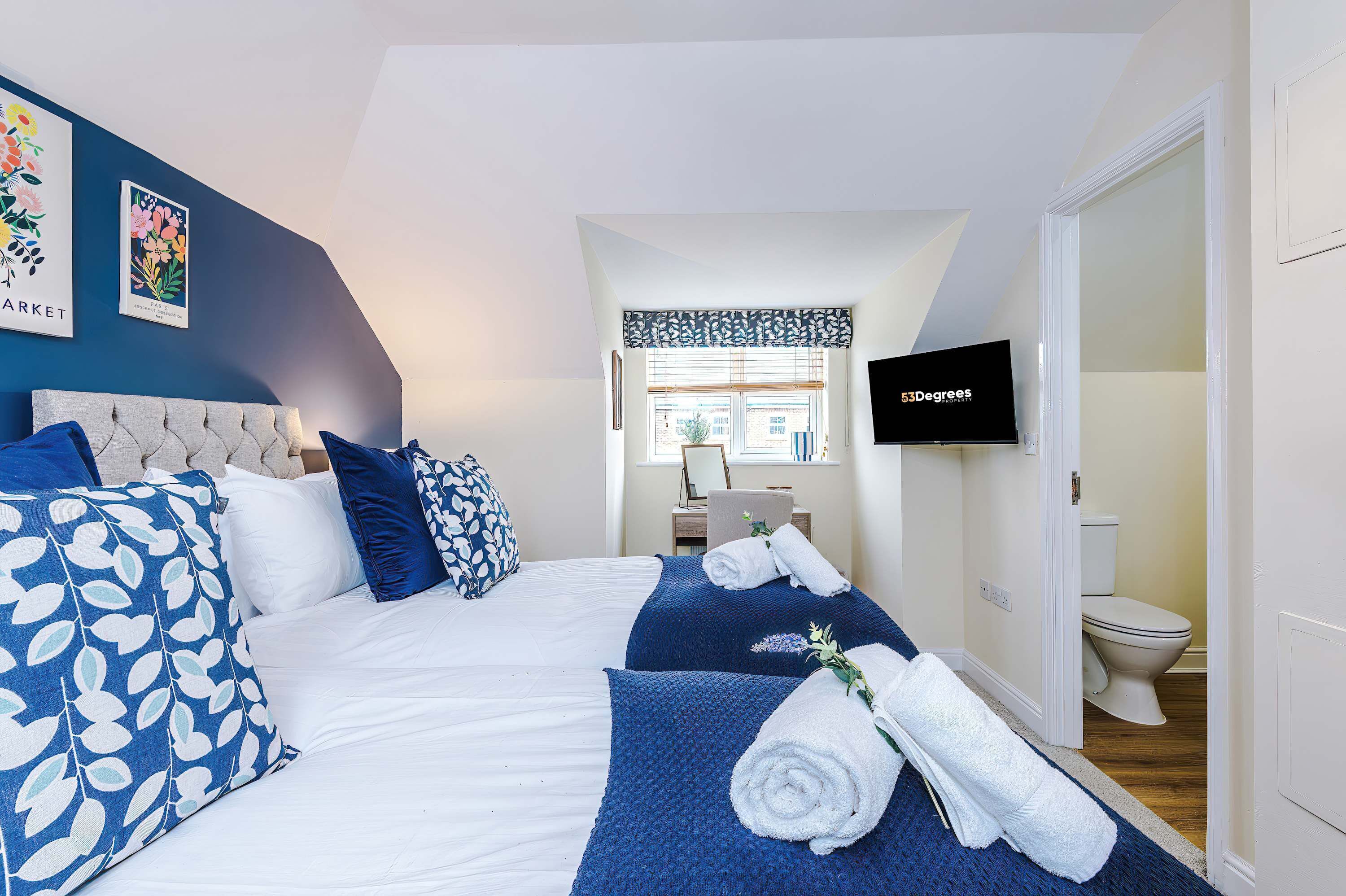 A hotel room with a bed, a TV, a bathroom, and a window with a view.