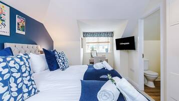 A hotel room with a bed, a TV, a bathroom, and a window with a view.