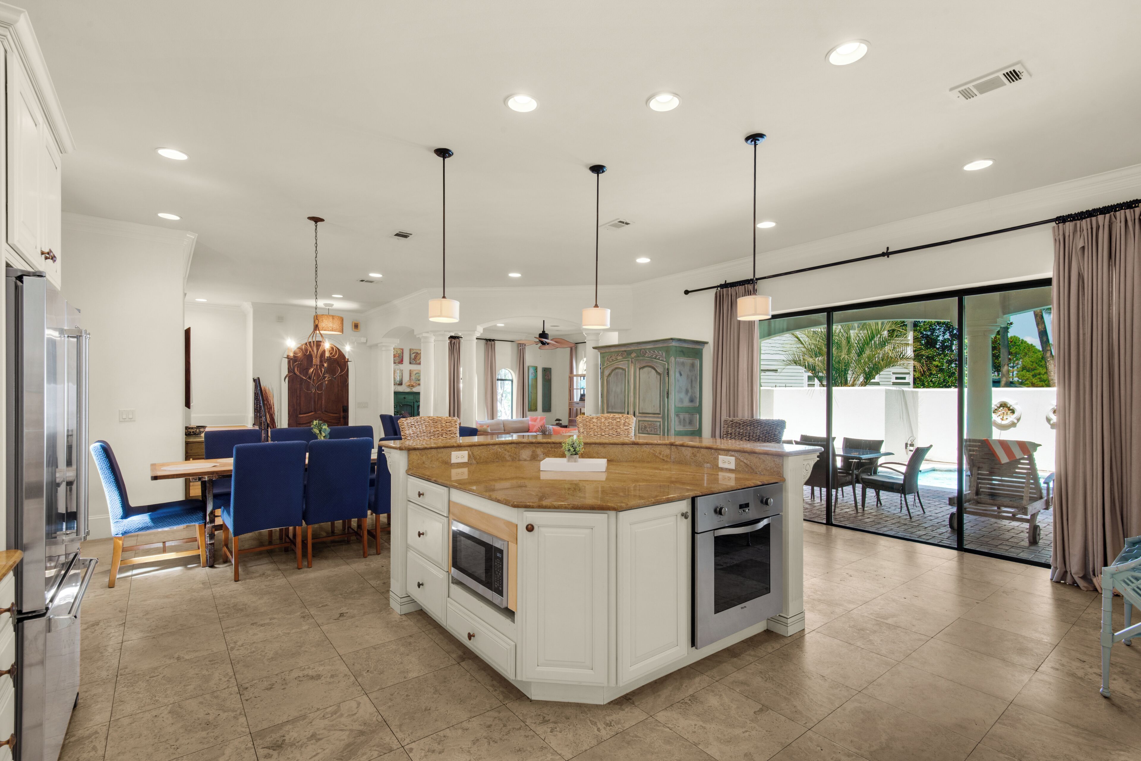 A spacious kitchen with a large island, modern appliances, and a dining area with blue chairs.