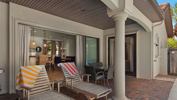 Een overdekt terras met lounge fauteuils en een eettafel.