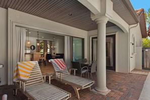 Ein überdachter Außenbereich mit Lounge-Möbeln und einem Esstisch.
