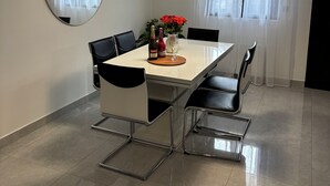 Un'area pranzo con tavolo, sedie, ventilatore a soffitto, specchio e finestra con tende.