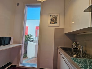 Eine kleine Küche mit Mikrowelle, Spüle und kleinem Fenster.