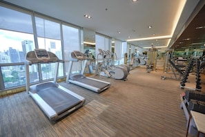 Ein Fitnessstudio mit Laufbändern, Crosstrainern und Gewichten.