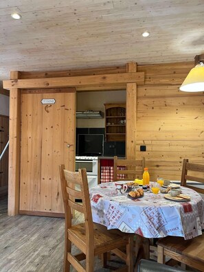A wooden interior with a dining table set for breakfast, a kitchen area, and a door labeled 'CUISINE'. - Fireplace or stove, parking, tv, 40m², Peisey-Vallandry (Peisey-Nancroix)