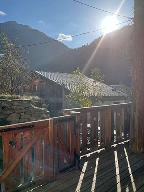 A wooden deck with a metal gate, a stone wall, and a mountain backdrop. - Fireplace or stove, parking, tv, 40m², Peisey-Vallandry (Peisey-Nancroix)